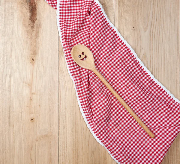 Rode handdoek en lepel op bruine houten achtergrond — Stockfoto
