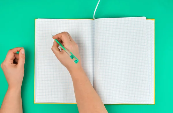 Pluma de mano femenina, cerca de cuaderno abierto en blanco en una celda — Foto de Stock