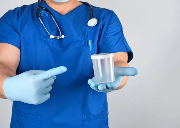 Lékař v modré jednotné a latexové rukavice drží prázdné plas — Stock fotografie