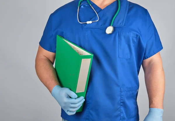 Doctor en uniforme azul, guantes estériles de látex sostiene en su mano un — Foto de Stock