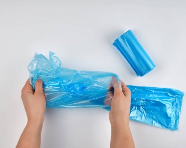 beyaz bir arka plan üzerinde ellerde mavi plastik çöp torbası