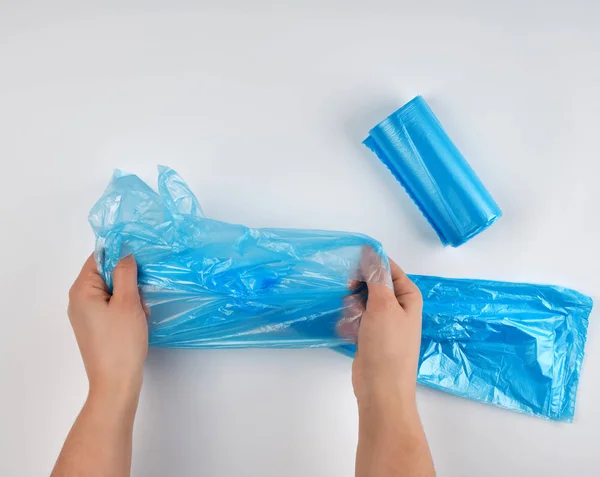 सफेद पृष्ठभूमि पर हाथों में नीला प्लास्टिक कचरा बैग — स्टॉक फ़ोटो, इमेज