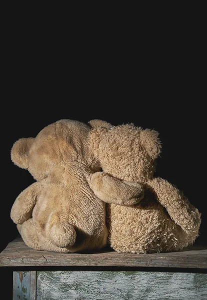 Twee oude bruine teddyberen zitten knuffelen op een houten oppervlak — Stockfoto