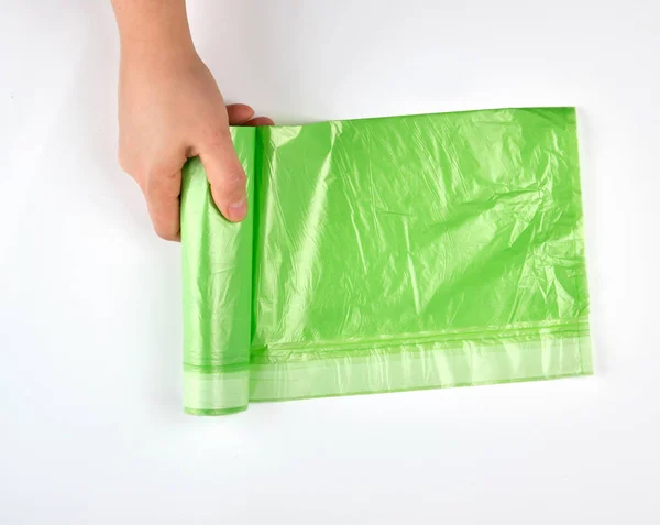 Weibliche Hand wickelt grüne Rolle mit Plastiktüten für Müll ab — Stockfoto