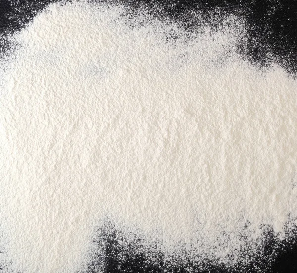 Posypane białą mąką na czarnym stole — Zdjęcie stockowe