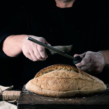 siyah üniformalı şef bir mutfak bıçağı keskinleştirir