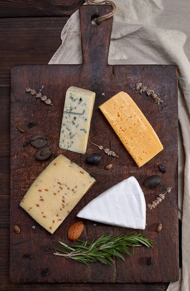Trozos de diferentes quesos sobre una tabla de madera marrón: brie, roque — Foto de Stock
