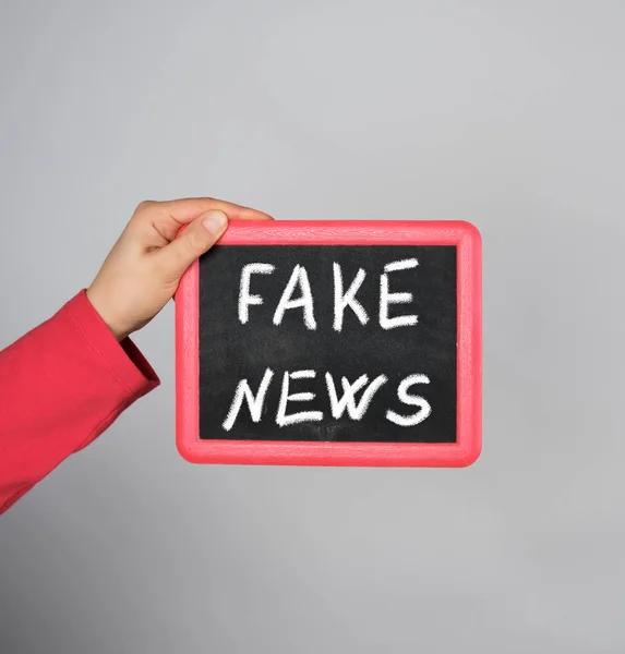 Female hand holding  red frame with chalk inscription fake news — Stock Photo, Image