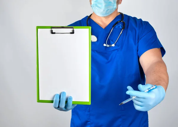 Arzt in blauer Uniform und sterilen Latex-Handschuhen hält ein Papier cl — Stockfoto