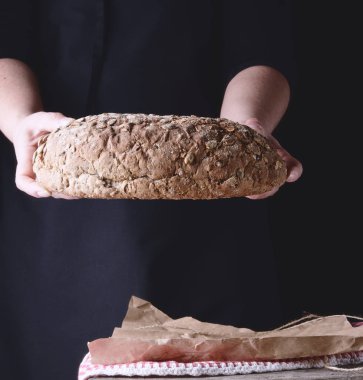 kadın elleri kabak çekirdeği ile oval pişmiş çavdar ekmeği tutun