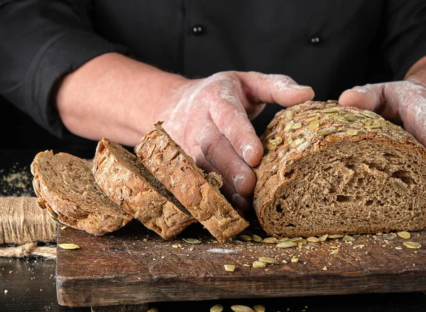 kahverengi ahşap bir tahta üzerinde kabak çekirdeği ile dilimlenmiş çavdar ekmeği