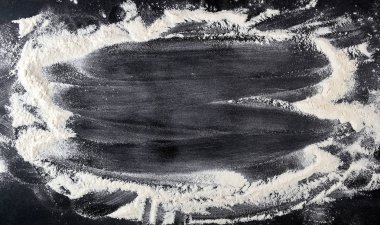 siyah bir masaya dağılmış beyaz buğday unu