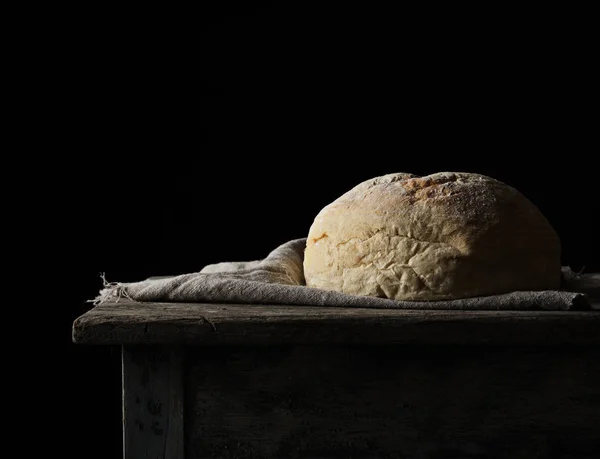 Baked round white wheat bread on a textile towel, wooden old tab — Stock Photo, Image