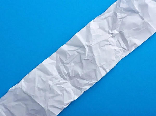 A gyűrött üres fehér papír kék háttéren — Stock Fotó