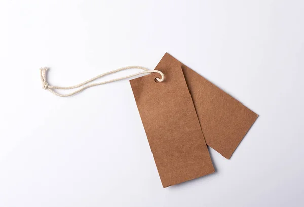 Etichetta marrone carta vuota sulla corda, sfondo bianco — Foto Stock