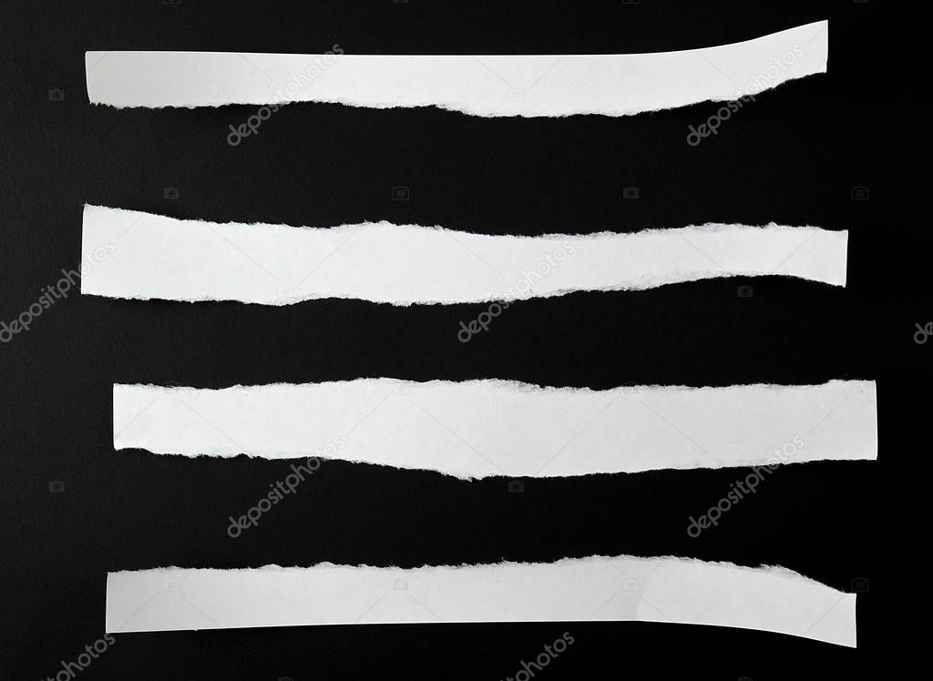 torn blank white paper strips against a black background