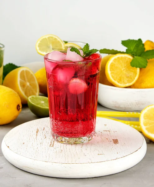 red strawberry lemonade in a glass on a round white wooden board