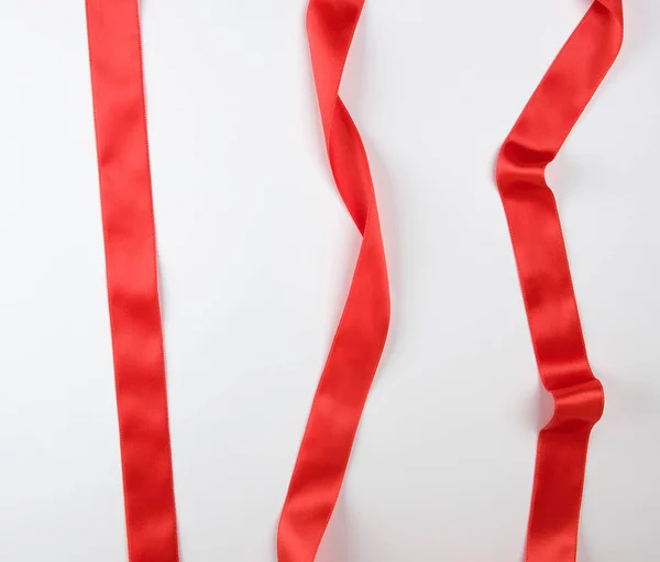 Beyaz bir arka plan üzerinde kıvrılmış kırmızı saden şerit — Stok fotoğraf