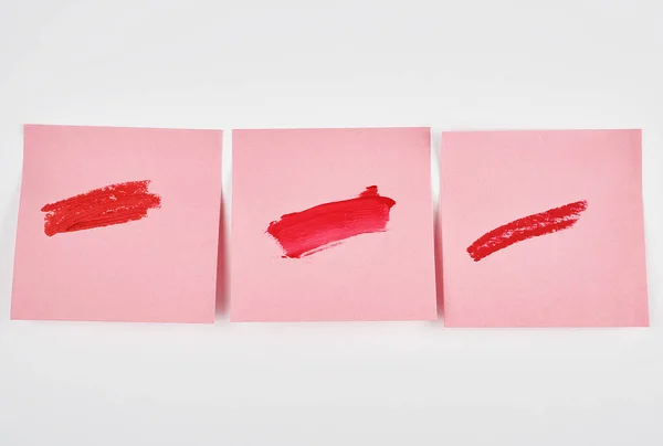 Frottis de rouge à lèvres rouge sur un autocollant en papier rose — Photo