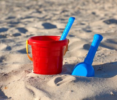 kırmızı plastik kova ve mavi tırmık, kum üzerinde kürek