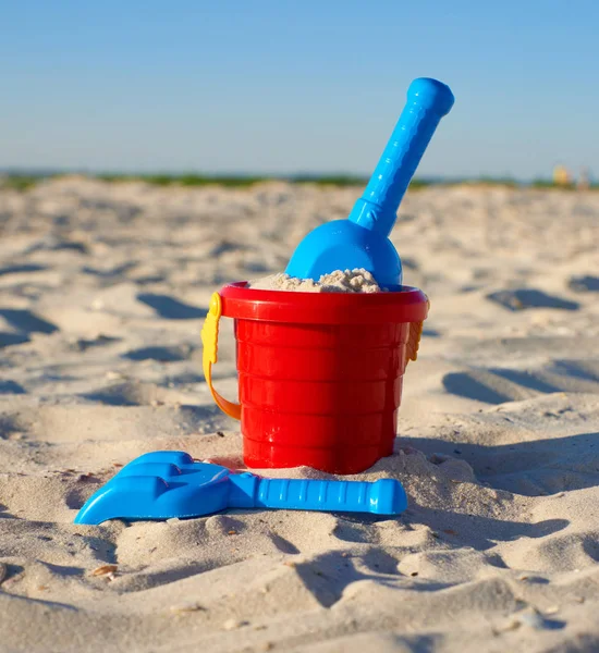 Красное пластиковое ведро и синие грабли, лопата на песке — стоковое фото