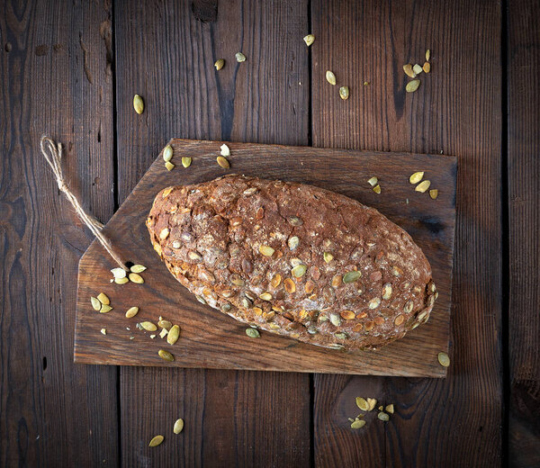 испеченный овальный хлеб из ржаной муки с тыквенными семечками
