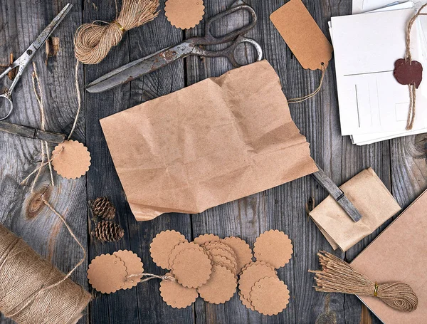 coil of brown rope, paper tags and old scissors on a gray wooden