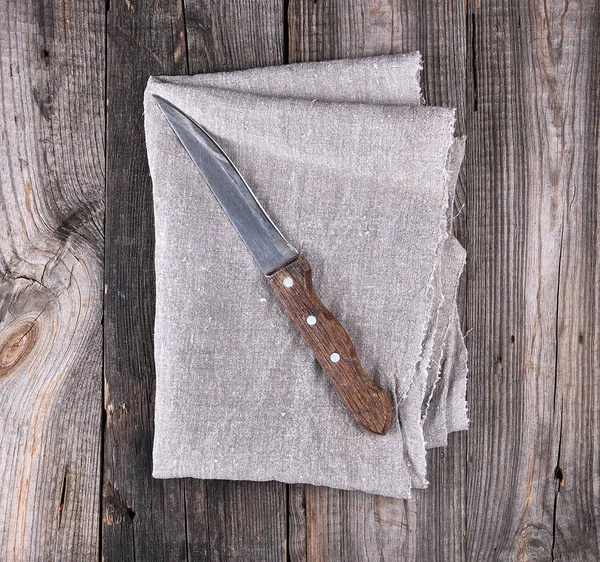 Старый кухонный нож на серой салфетке, деревянный фон — стоковое фото