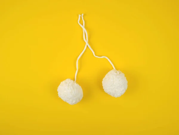 two white fluffy pom-poms of white cotton thread