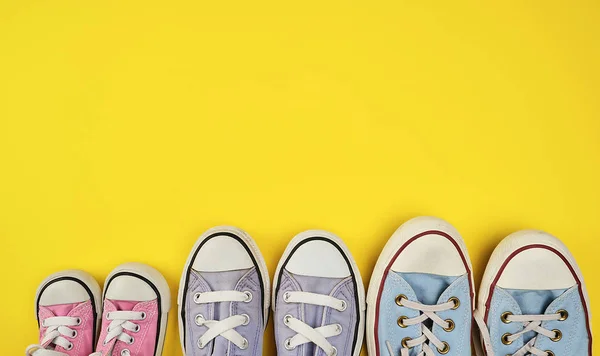 lot of textile worn sneakers of different sizes on a yellow back