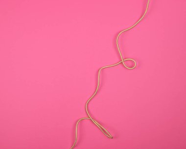 pembe arka plan üzerinde bir tekstil sargı bükülmüş altın kablo