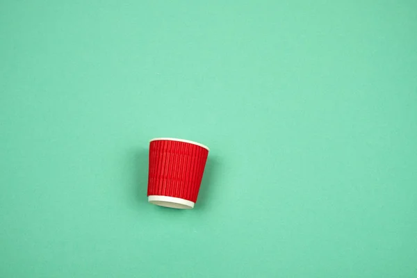 Taza de papel rojo con bordes corrugados para bebidas calientes en una ba verde —  Fotos de Stock