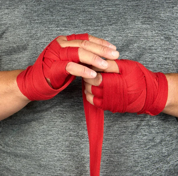 Mãos envolvidas em uma bandagem esportiva elástica vermelha — Fotografia de Stock