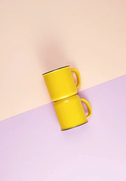 Dos tazas de cerámica amarilla con asa sobre un fondo pastel abstracto — Foto de Stock