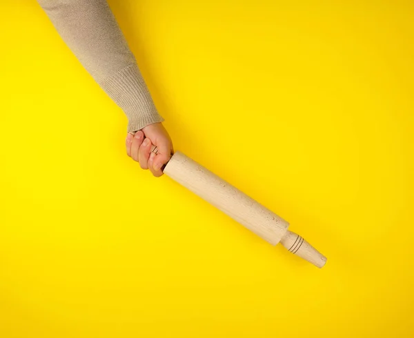 Ręcznie trzymając drewniany wałek na żółtym tle — Zdjęcie stockowe