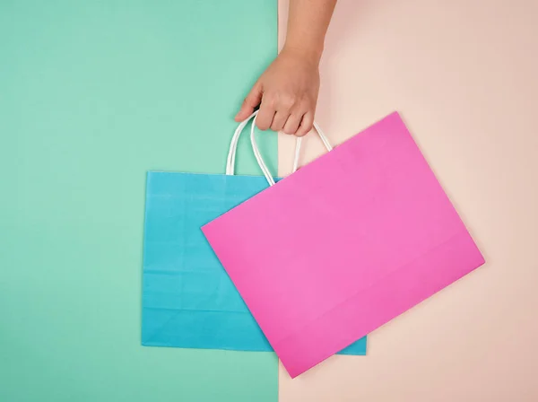 Mão segurando dois sacos de compras de papel em um fundo pastel — Fotografia de Stock