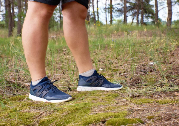 male legs of athlete runner in blue shoes in the middle of the f