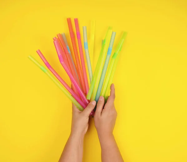 Mano femenina sosteniendo tubos de cóctel de plástico multicolor — Foto de Stock