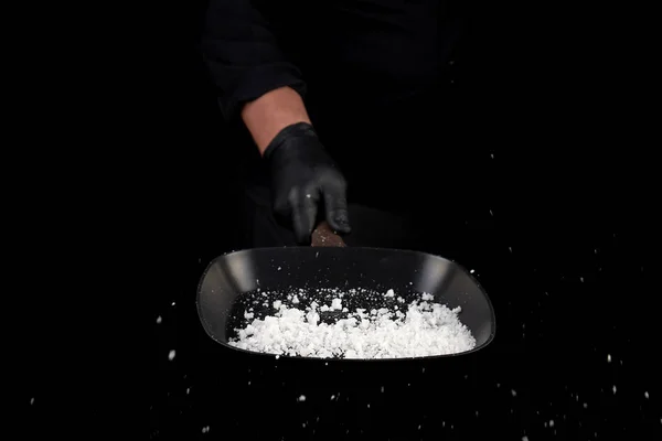 Chef en uniforme negro sostiene una sartén con sal blanca y vomita — Foto de Stock