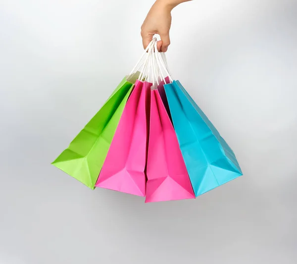 Mano femminile che tiene quattro sacchetti di imballaggio di carta colorata — Foto Stock