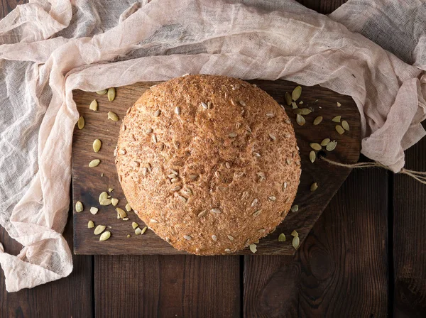 Pane di segale rotondo al forno con semi di girasole su un tovagliolo tessile — Foto Stock