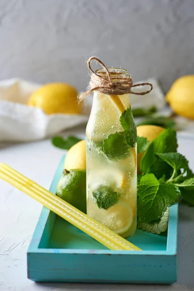 Bebida fría con limones, hojas de menta, lima en una botella de vidrio — Foto de Stock