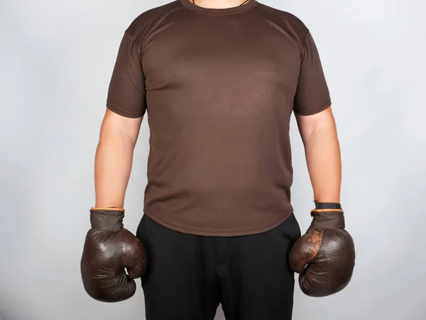 Junger Mann steht mit sehr alten, braunen Boxhandschuhen auf — Stockfoto