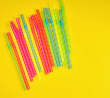 sarı arka planda çok renkli plastik kokteyl tüpleri