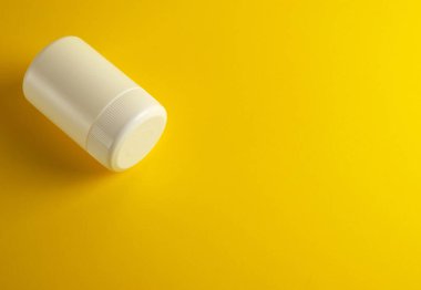 sarı bir arka plan üzerinde ilaçlar için kapalı beyaz plastik kavanoz