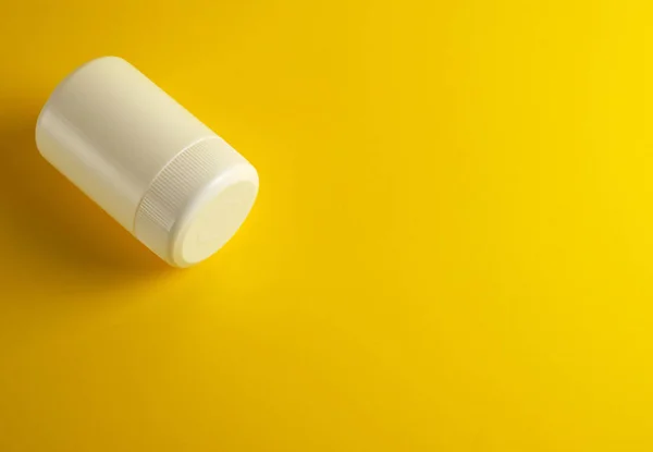 Zamknięty biały plastikowy słoik dla leków na żółtym tle — Zdjęcie stockowe