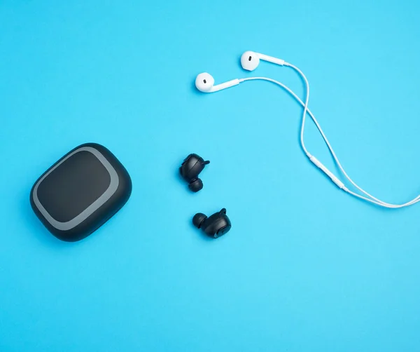 black wireless and white earphones with wire on a blue backgroun