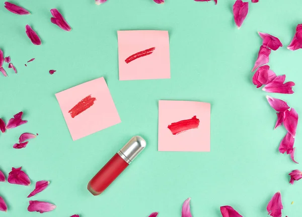 Batom líquido e um esfregaço de batom vermelho em um papel rosa stic — Fotografia de Stock