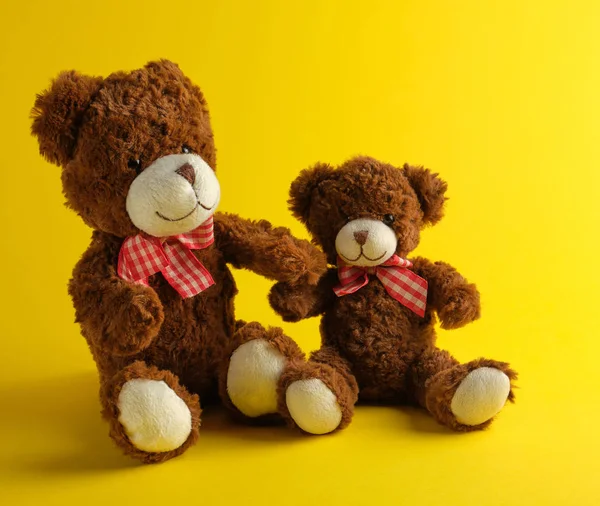 Dois ursinhos de pelúcia marrom em um fundo amarelo — Fotografia de Stock