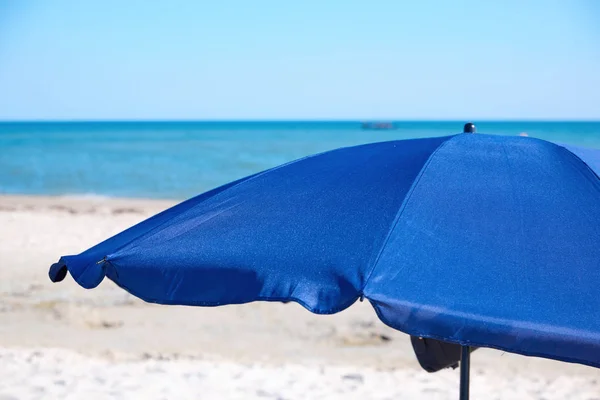 Parasol de plage textile bleu ouvert sur un littoral sablonneux — Photo